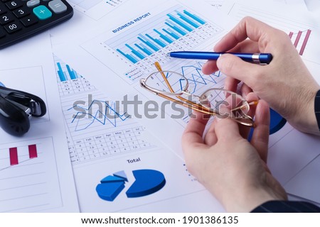 business graph, sales report, calculator, pen and glasses in a hands