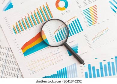 Business graphs, charts and magnifying glass on table. Financial development, Banking Account, Statistics