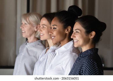 Business group of four professional confident diverse age multicultural female partners executives teammates stand in oblique line look forward with smile. Focus on millennial asian businesswoman face