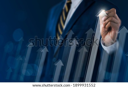 Business growth, boost up business, progress in business or success concept. Businessman is drawing raising arrow graph on dark tone background.