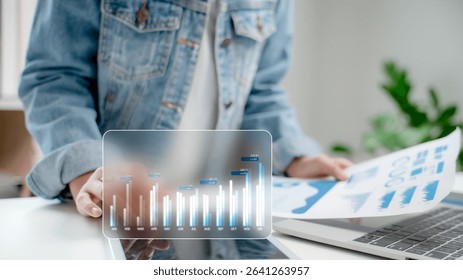 Business growth concept with person analyzing digital bar chart and paper report. Financial data visualization, analytics strategy, and modern technology for corporate success.
