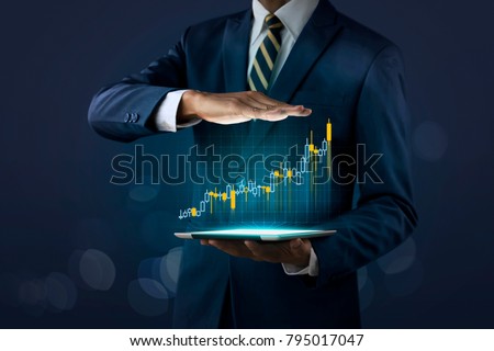 Business growth, progress or success concept. Businessman is showing a growing virtual hologram stock on dark tone background.
