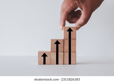 Business Growth and Success,economic or business improvement concept.,Hand stacking wooden blocks with arrow up icon over white background for Goal strategy idea. - Shutterstock ID 2311826183