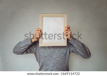 Business Guy hides his face with a picture frame - Concept for marketing, target audience determination, buyer persona