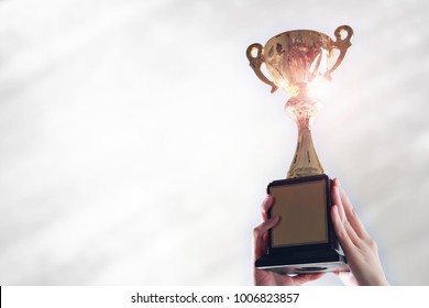 Business hands holding trophy cup on white background.