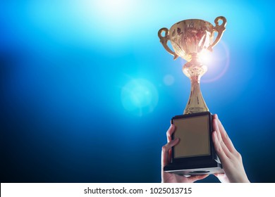 Business hands holding trophy cup on deep blue background. - Shutterstock ID 1025013715