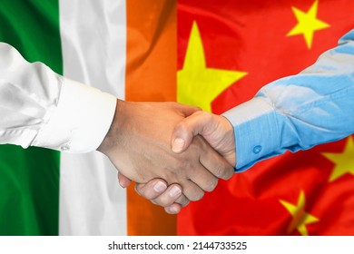 Business Handshake On Background Of Two Flags. Men Handshake On Background Of Ireland And China Flag. Support Concept