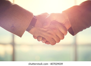 Business Handshake. Business Handshake And Business People Concept. Two Men Shaking Hands Over Sunny Office Background. Partnership, Deal