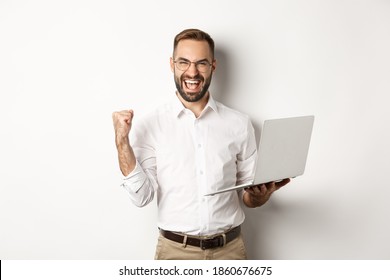 Business. Happy Manager Winning Online, Rejoicing With Fist Pump, Holding Laptop And Triumphing, Standing Over White Background