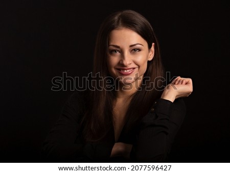 Business happy smiling thinking woman with natural makeup looking with hand near the face arms in black t-shirt on dark shadow black background. Closeup front view face portrait