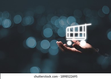 Business holding virtual shopping cart trolley with blue bokeh , Online shopping concept.