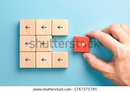 Business icon for innovative, solution, Unique, think different and individual concept, Businessman hand choose red wooden blocks with arrow individual pointing in the different way