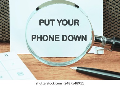 Business idea end telephone connection. PUT YOUR PHONE DOWN through a magnifying glass on a clean white sheet - Powered by Shutterstock