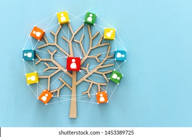 Business image of wooden tree with people icons over blue table, human resources and management concept