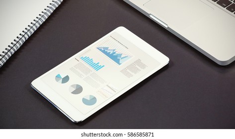 Business interface with graphs and data against composite image of digital screen, laptop and notebook