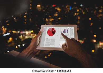 Business interface with graphs and data against man using digital tablet in the balcony