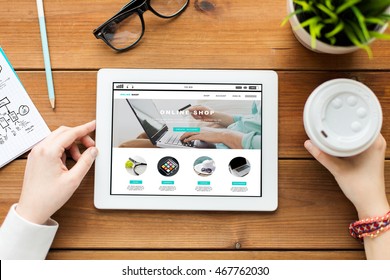 Business, Internet Shopping, Technology And People Concept - Close Up Of Woman With Online Shop Web Page On Tablet Pc Computer Screen, Notebook And Coffee On Wooden Table