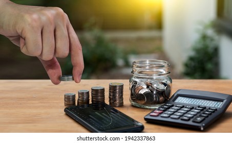 Business investment growth concept. hand holding of coins with with smartphone and calculator on wood table, Saving money. - Powered by Shutterstock