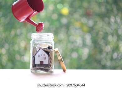 Business investment and real estate concept, Woman hand holding watering can with model house and gold coin money in the glass bottle on green background, Finance and Banking - Shutterstock ID 2037604844
