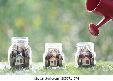 Business investment and real estate concept, Woman hand holding watering can with model house and gold coin money in the glass bottle on green background, Finance and Banking - Shutterstock ID 2052714074
