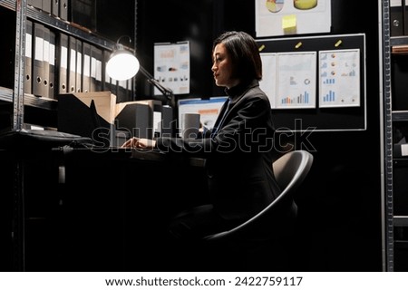 Business invoicing employee woman imputing accountancy market data analysis paperwork on laptop with cup of coffee in hand. Archival depository with folders in cabinet bookshelves and flowcharts