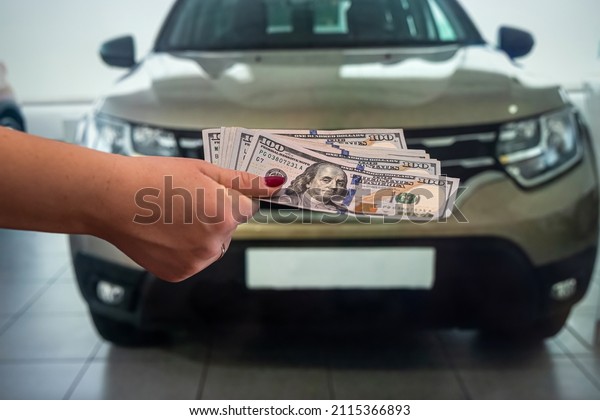 a business lady in a car showroom received a\
large sum of dollar bills for a new car. The concept of buying a\
car. Car interior concept.