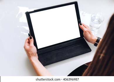 A business lady holding a tablet in her hands sitting in front of a white table, back view mockup - Shutterstock ID 406396987