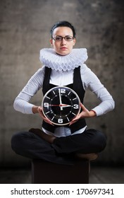 Business Lady In Ruff Collar With A Clock Looking At Camera