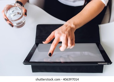 A business lady working with a tablet, holding a glass of water and sitting in front of a white table, top view - Shutterstock ID 406397014