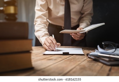Business lawyer working hard at office desk workplace with book and documents. - Powered by Shutterstock