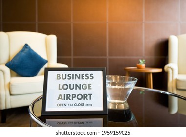 The Business Lounge Airport Service Time Sign Is Placed On A Modern Round Tempered Glass Table.