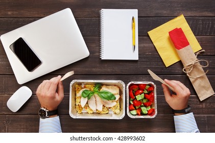 Business Lunch At Working Place. Businessman In Office. Healthy, Diet Food Take Away In Foil Boxes: Roasted Turkey With Salad. Cell Phone, Mobile, Fitness Bracelet On Hand. Top View, Flat Lay