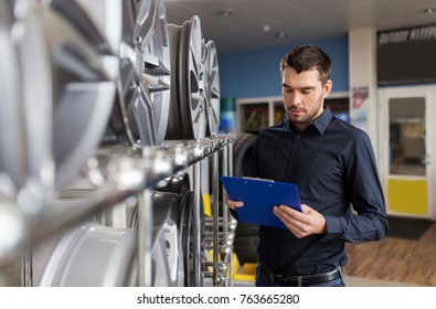 Business, Maintenance And People Concept - Male Manager With Alloy Wheel Rims And Clipboard At Car Repair Service Or Auto Store