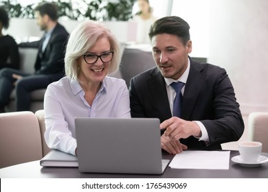 Business Man And 50 Years Old Woman Colleagues Looking At Laptop Happy Smiling. Businessman And Businesswoman Sitting And Working Together Discussing Successful Strategy Results On Computer Monitor