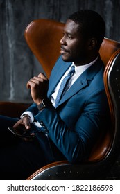 Business man african american sitting in a loft armchair with a phone in his hands.