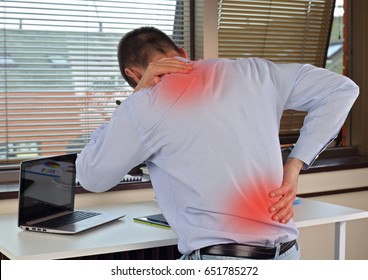Business man with back pain in an office . Pain relief concept