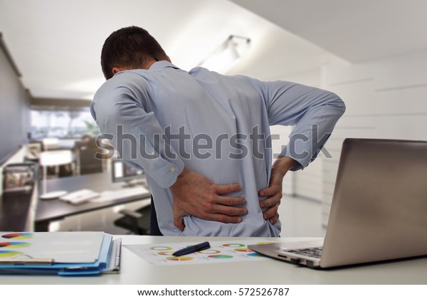 Business man with back pain an office . Pain\
relief concept