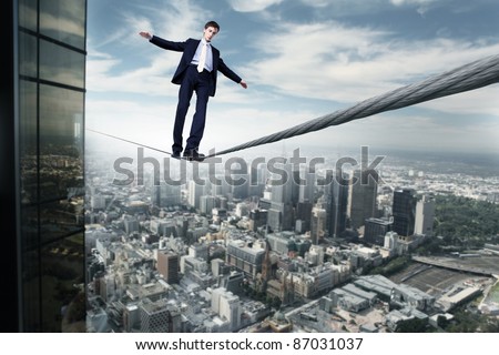 Business man balancing on the rope high in the sky