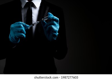 Business Man In Balck Business Suit With Medical Gloves Holding Syringe, Coronavirus Vaccine For Prevention Coronavirus, Covid-19 On Black  Background And Copy Space. Business Covid-19 Vaccine Concept