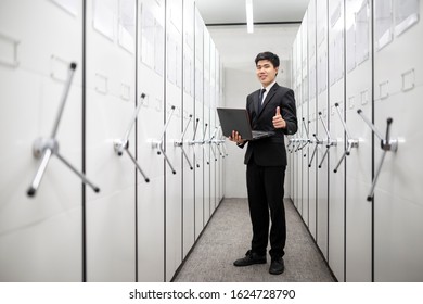 Business Man, Bank Manager Using Notebook In A Locker Server Room, Safe Deposit Boxes With Vault Door.