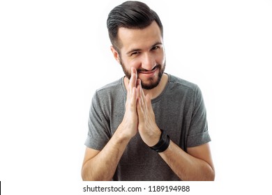 A business man with a beard, a gray t-shirt, with a crafty expression that he came up with, rubbing his hands in front of him, isolated on a white background