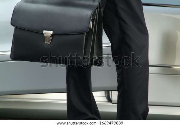 business\
man with black leather bag near his luxury\
car