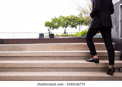 Business Man In A Black Suit And Leather Shoes Walking Up The Stairs With Blank Space For Adding Text.