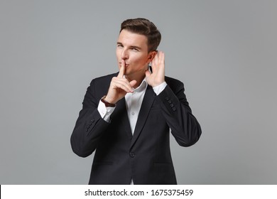 Business Man In Black Suit Shirt Posing Isolated On Grey Background. Achievement Career Wealth Business Concept. Mock Up Copy Space. Say Hush Be Quiet With Finger On Lips Shhh Gesture Try To Hear You