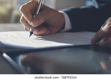 Business man in black suit signing contract document with ldigital tablet on office desk, deal concept, close up - Shutterstock ID 768792514