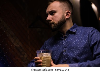 Business man, in blue shirt and glasses, drinking cocktail of vintage old fashion glass in loft bar
