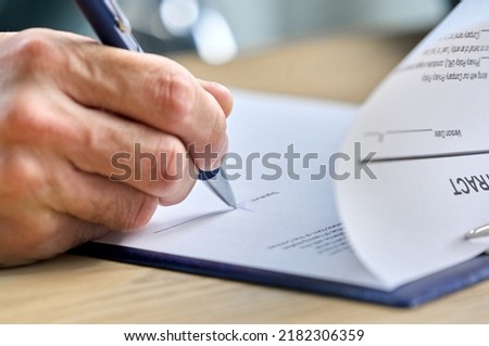 Business man ceo executive putting hand signature on document, businessman holding pen writing signing contract on table committing bank loan agreement investment legal deal concept. Close up view