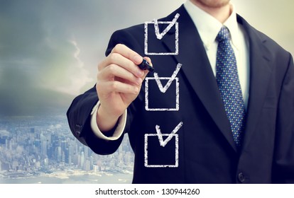 Business man checking off check boxes with cityscape background