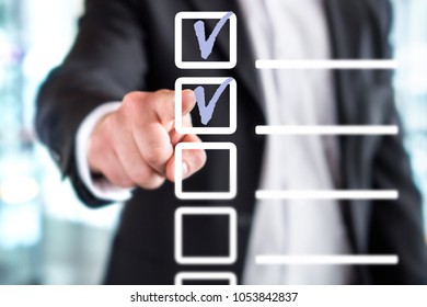Business man with checklist and to do list. Man writing and drawing v sign check marks with hand and finger in square box. Project management, planning and keeping score of completed tasks concept. - Shutterstock ID 1053842837