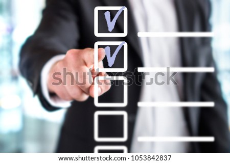Business man with checklist and to do list. Man writing and drawing v sign check marks with hand and finger in square box. Project management, planning and keeping score of completed tasks concept.